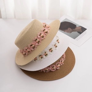 Detail of straw sun hats in three colors featuring handmade floral ribbon decorations