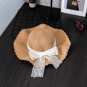 Detailed view of the woven straw texture with elegant white lace bow and wavy brim edge