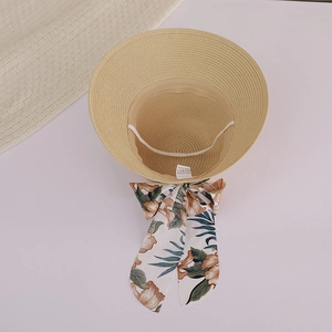Detail of wide brim straw sun hat featuring floral ribbon bow and inner windproof strap