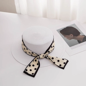 Detail of white straw boater hat with a chic black polka dot ribbon and elegant bow accent