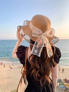 Detail of elegant straw sun hat with floral embroidery and white lace bow decoration