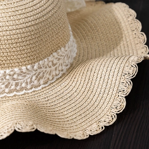 Detail of summer straw hat featuring elegant white lace edges and scallop brim texture