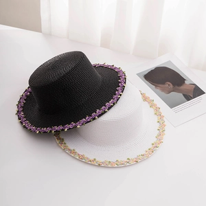 Detailed embroidery of floral patterns on flat top straw boater hats in black and white