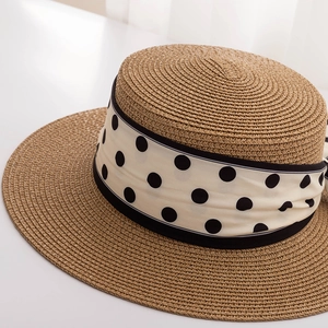 Close-up of woven boater hat featuring a white and black polka dot ribbon detail