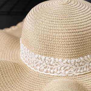 Close-up of fine beige straw weave texture and delicate white lace ribbon on sun hat