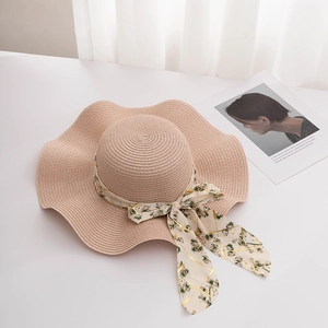 Détail d'un chapeau de paille à larges bords avec ruban en mousseline et bords ondulés
