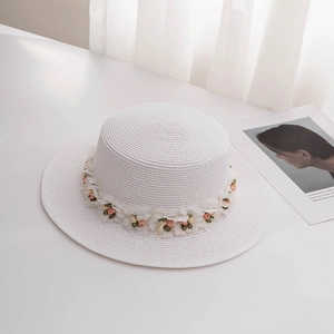 Detailed macro view of white straw boater hat with delicate fabric flower decorations