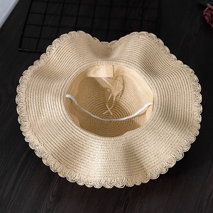 Detail view of the woven texture and windproof rope inside this beige straw sun hat