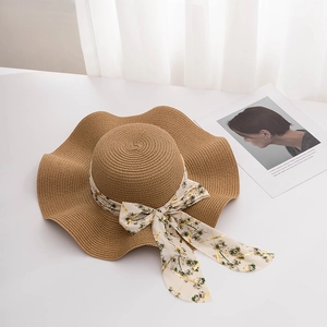 Vue détaillée d'un chapeau de paille beige à large bord avec un n d en mousseline fleurie