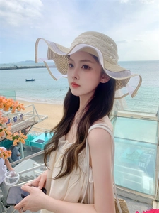 Detailed view of women's straw sun hat with pearls, lace decor, and wavy brim on beach