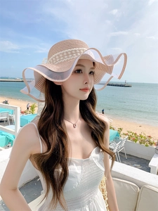 Dettaglio cappello di paglia con pizzo elegante e tesa ondulata per protezione solare