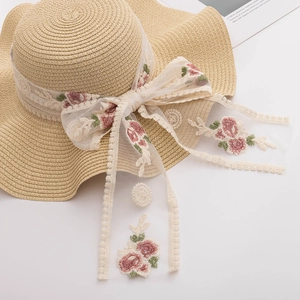 Detail of summer straw hat with floral embroidery lace ribbon and elegant bow accent