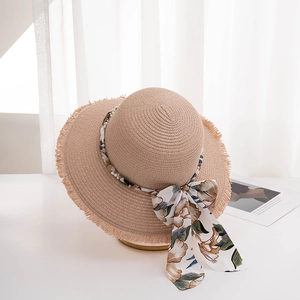 Detail of straw hat with pearl string, floral ribbon and fringed edges for women