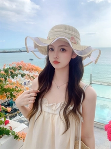 Close-up of pink floral embroidery and wavy white mesh brim on beige straw sun hat