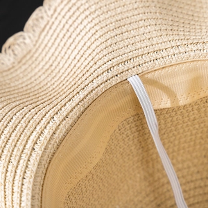 Detail view of woven straw hat interior featuring sweatband and white chin strap