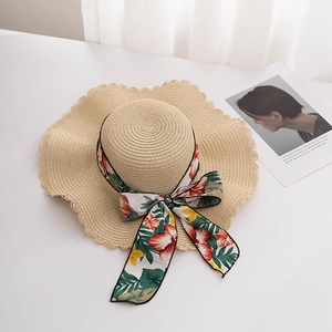 Detailed close-up of wide-brim straw hat with scalloped edge and floral bow ribbon