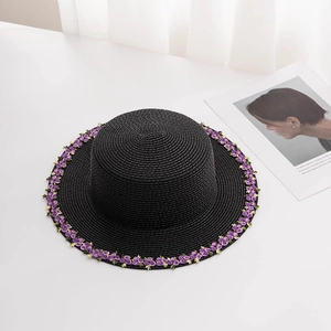 Close-up of black wide brim straw hat with purple floral embroidery and flat crown design