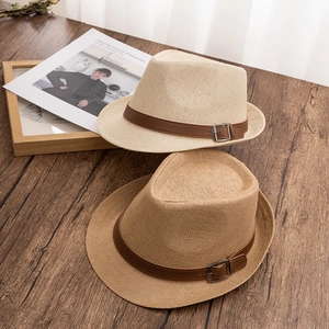 Classic straw fedora hats in beige and light brown with leather bands on wooden desk