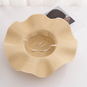 Detail view of woven straw sun hat featuring a wavy brim and adjustable wind rope