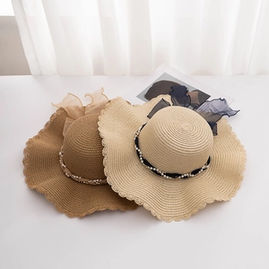 Elegant wide-brim straw sun hats with wavy edges, pearl chains, and mesh ribbons