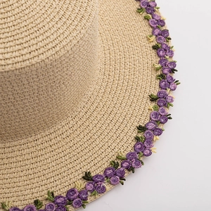 Detail of high-density straw sun hat with delicate purple floral embroidery on the brim