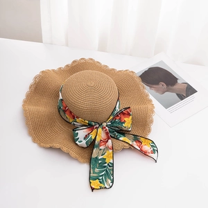 Detailed macro view of the straw hat's wavy brim design and floral printed silk ribbon