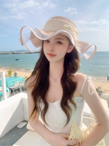 Detail of summer straw hat with lace wavy edge and pearl accents in a beach setting