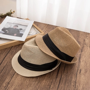 Classic summer straw fedora hats for men and women with black ribbon band on wood