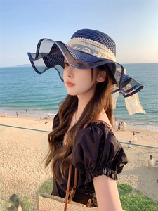 Detail of navy blue straw sun hat featuring elegant cream lace embroidery on wide brim
