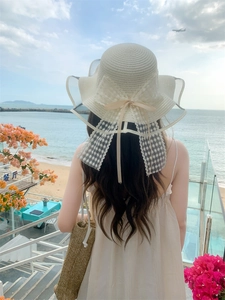Dettaglio di un cappello di paglia bianco a tesa larga con elegante fiocco in pizzo
