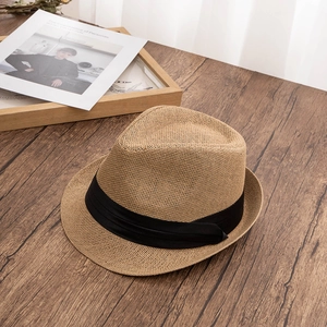 Classic straw fedora with black ribbon detail on a textured dark wood background