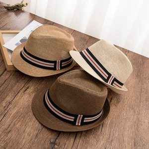 Chapeaux fedora en paille crème et marron avec ruban rayé sur table en bois