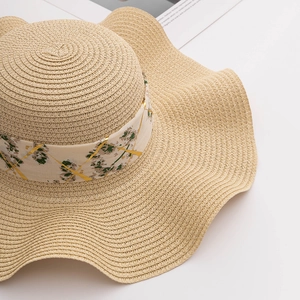 Détail de chapeau de paille à larges bords avec ruban en soie floral et texture tressée