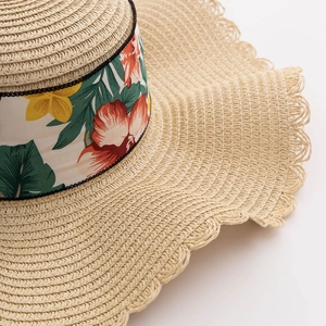 Detail of hand-woven straw hat brim with floral printed ribbon and scalloped edges