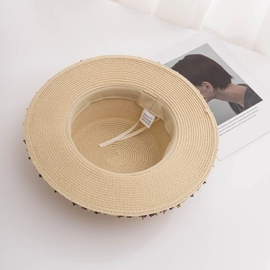 Detail view of beige straw hat interior with sweatband and floral brim accents