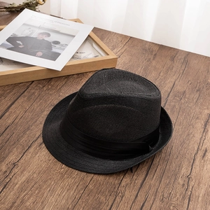 Close-up of black woven straw fedora hat texture with ribbon on dark wooden table