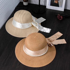 Top view of French straw hats with elegant silk ribbons and decorative pearl chains