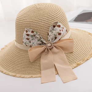 Detailed macro view of a straw sun hat featuring a large floral bow and frayed brim texture