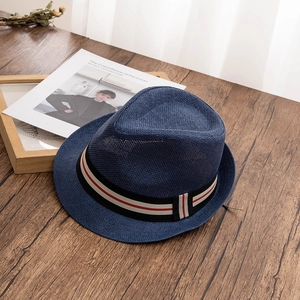 Détail du chapeau de paille bleu marine avec ruban rayé sur une table en bois