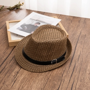 Detailansicht eines braunen Strohhutes mit schwarzem Lederband auf einem Holztisch