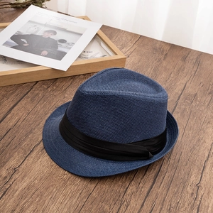 Detail of navy blue woven fedora hat with black satin band on wooden table surface