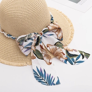 Detail of straw sun hat with floral chiffon ribbon, raw edges and pearl ornaments