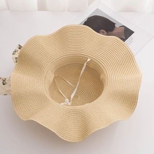 Détail d'un chapeau de paille d'été avec ruban floral et large bord ondulé élégant
