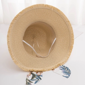 Close-up of straw sun hat interior showing tropical floral ribbon and elastic chin strap