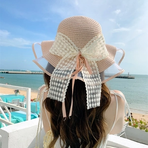 Vista posteriore del cappello di paglia rosa con fiocco in pizzo e tesa ondulata al mare