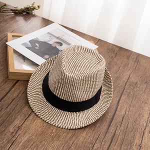 Close-up of dual-tone straw fedora hat on a vintage wooden desk with decorative props