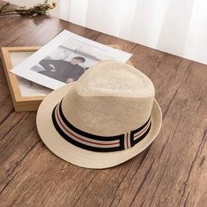 Détail d'un chapeau de paille Panama avec ruban rayé sur bureau en bois sombre