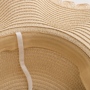 Close-up of straw sun hat interior showing dense weaving, sweatband, and elastic strap