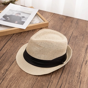 Detail of a beige woven straw Fedora hat with a stylish black ribbon band for summer