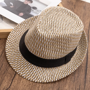 Close-up of classic straw fedora weaving texture and black band on wooden background